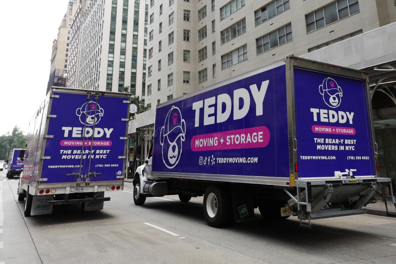 Three Teddy Moving & Storage trucks driving through NYC during a move